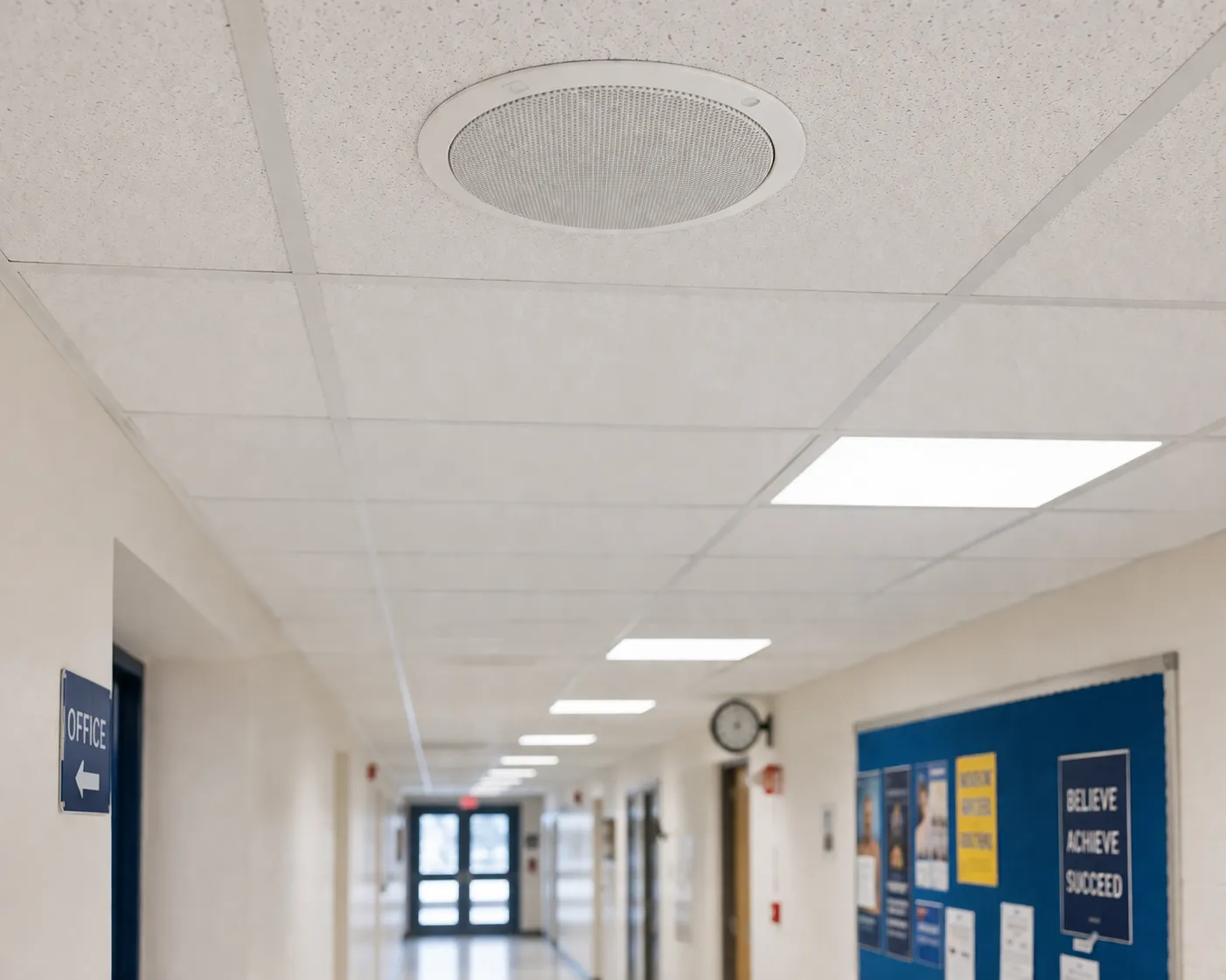 Altavoz de techo de megafonía instalado en un pasillo de colegio u oficina para anuncios de voz interiores claros